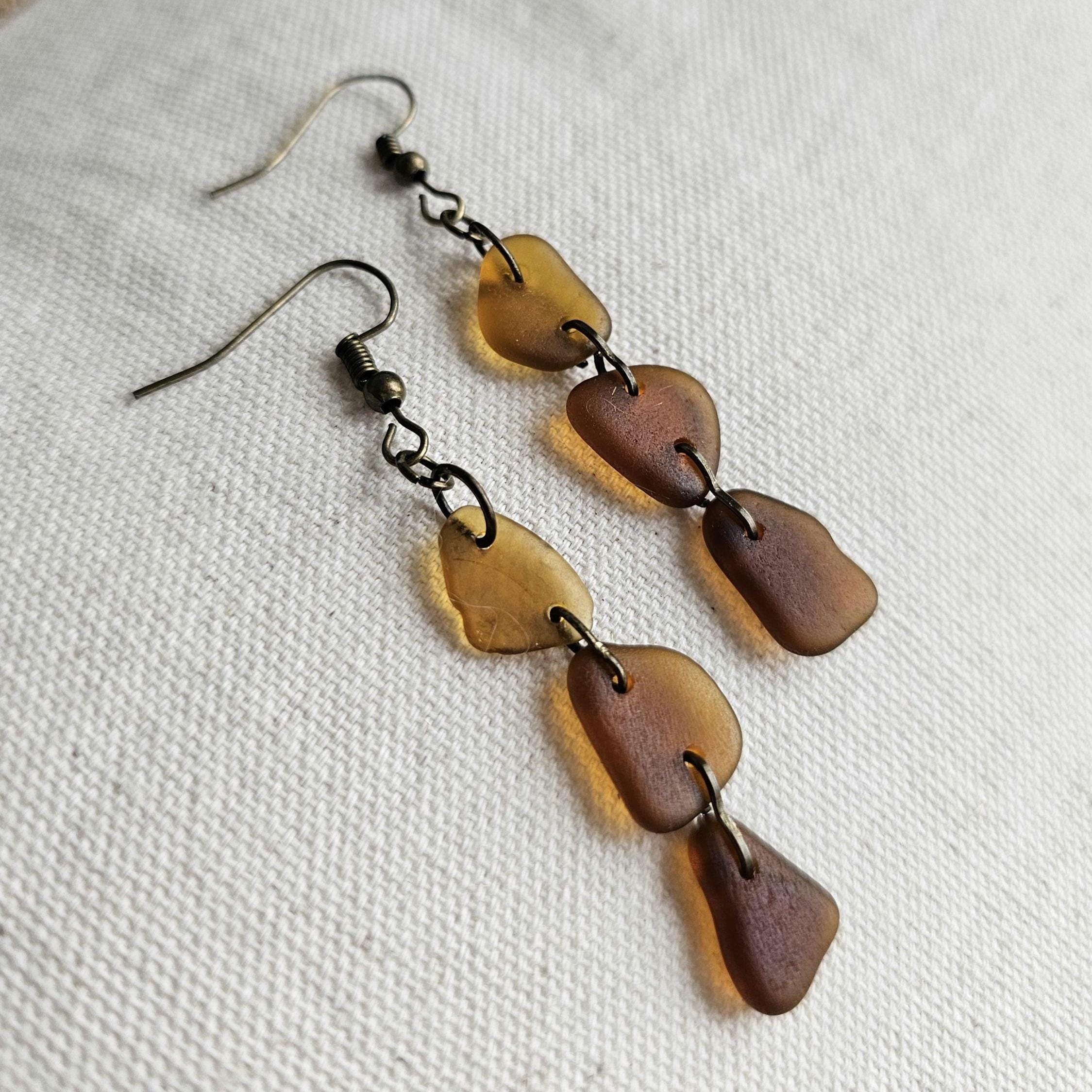 Pair of earrings with brown and gold disc shapes on a white fabric background