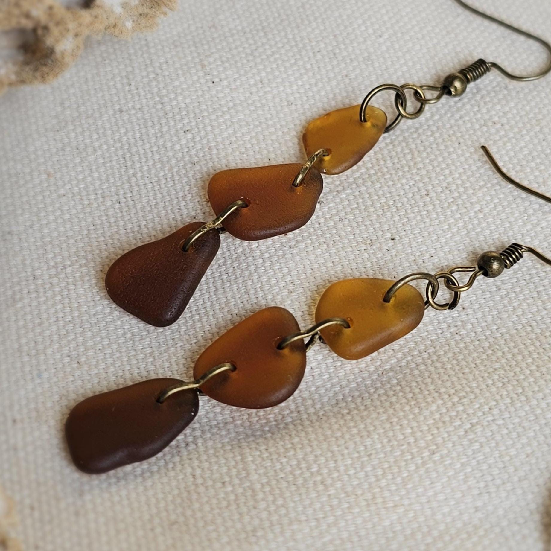 Pair of brown and gold earrings on a textured beige surface