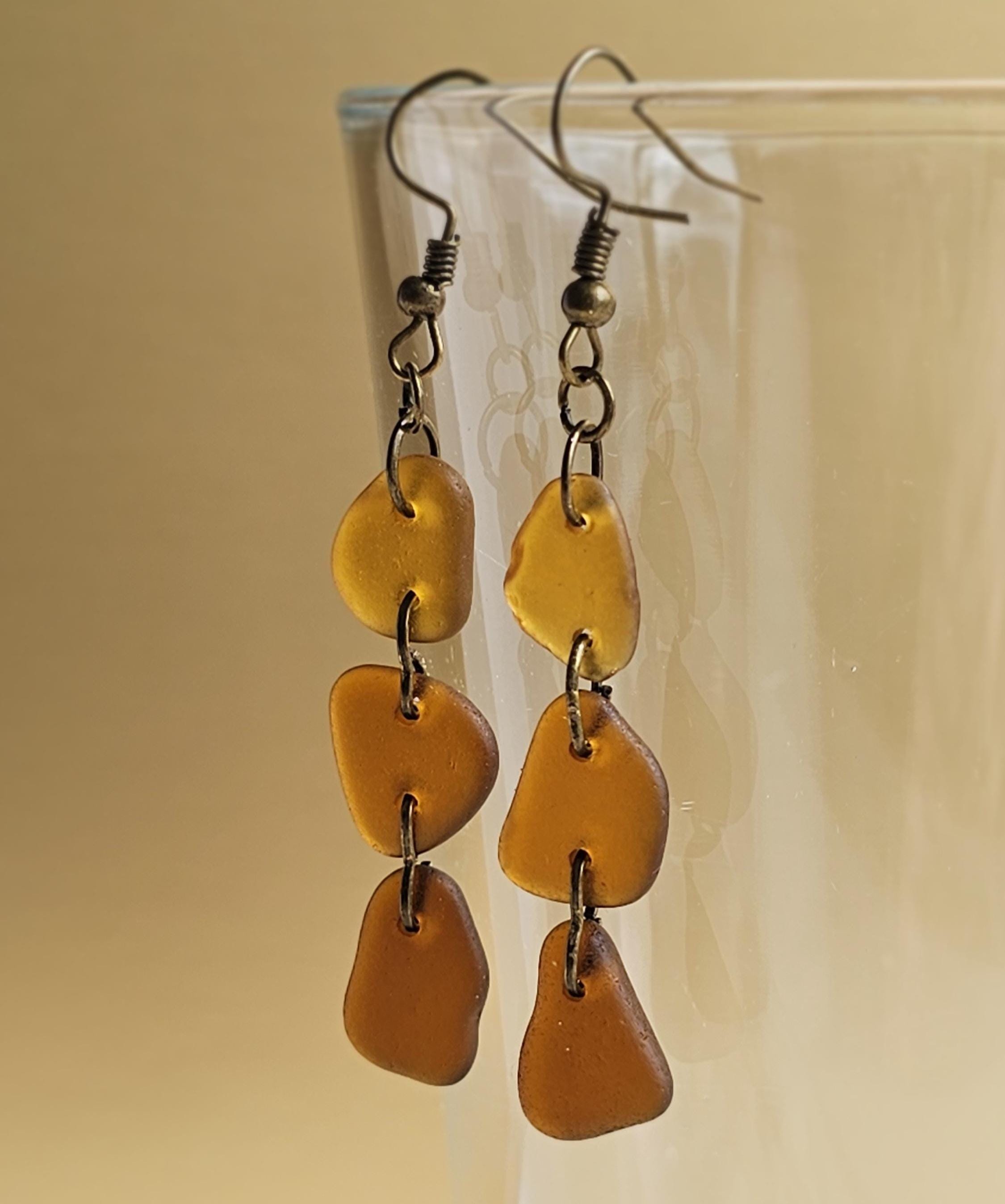 Pair of amber-colored drop earrings on a beige background