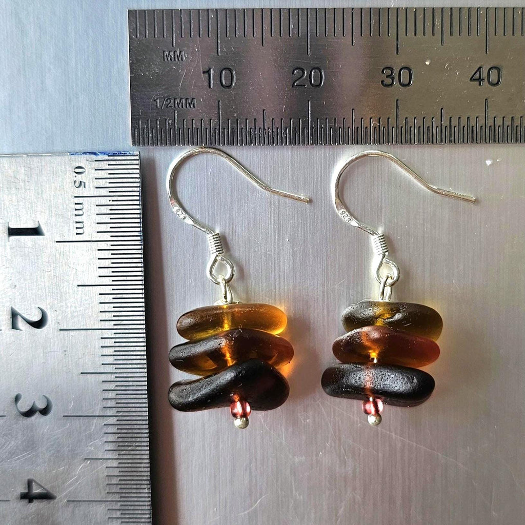 Pair of earrings with stacked sea glass on a metallic surface with rulers for scale.
