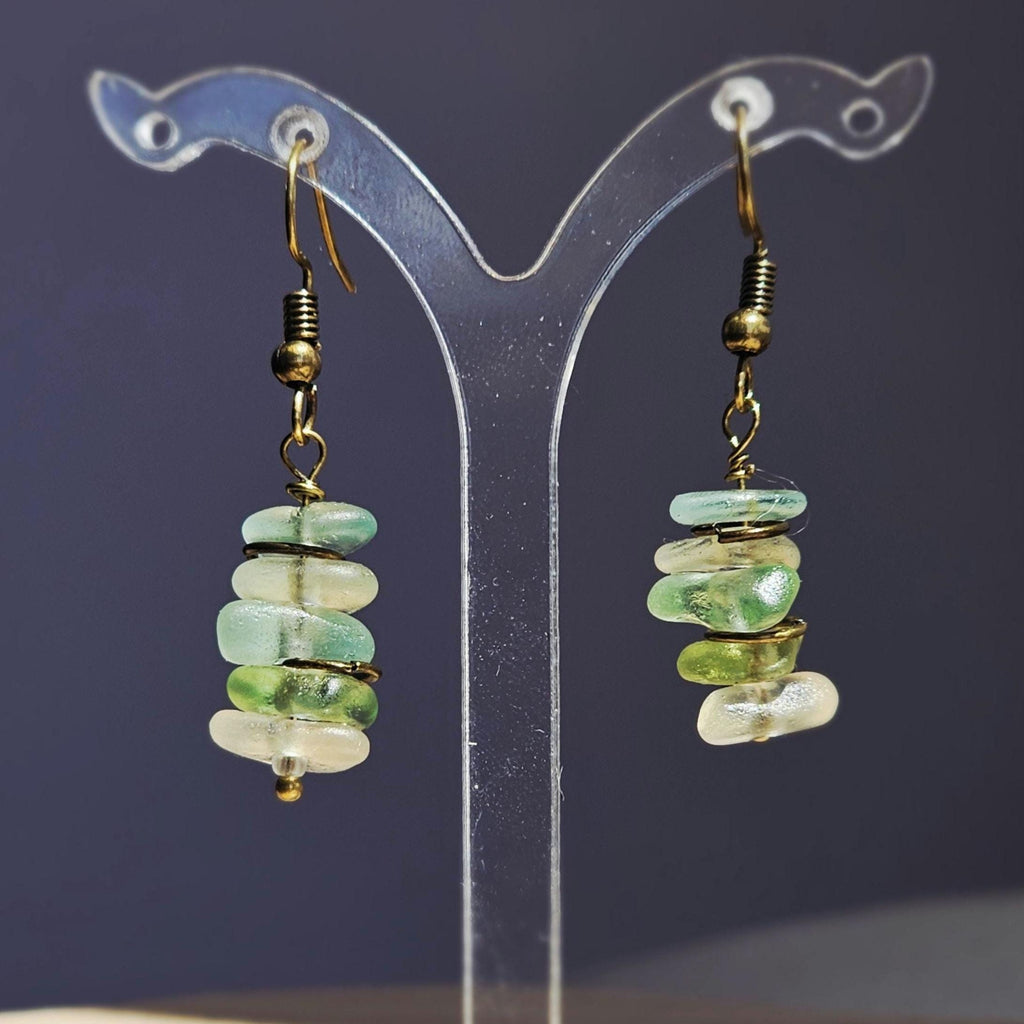 Pair of earrings with green, aqua and clear sea glass on a dark backgroud