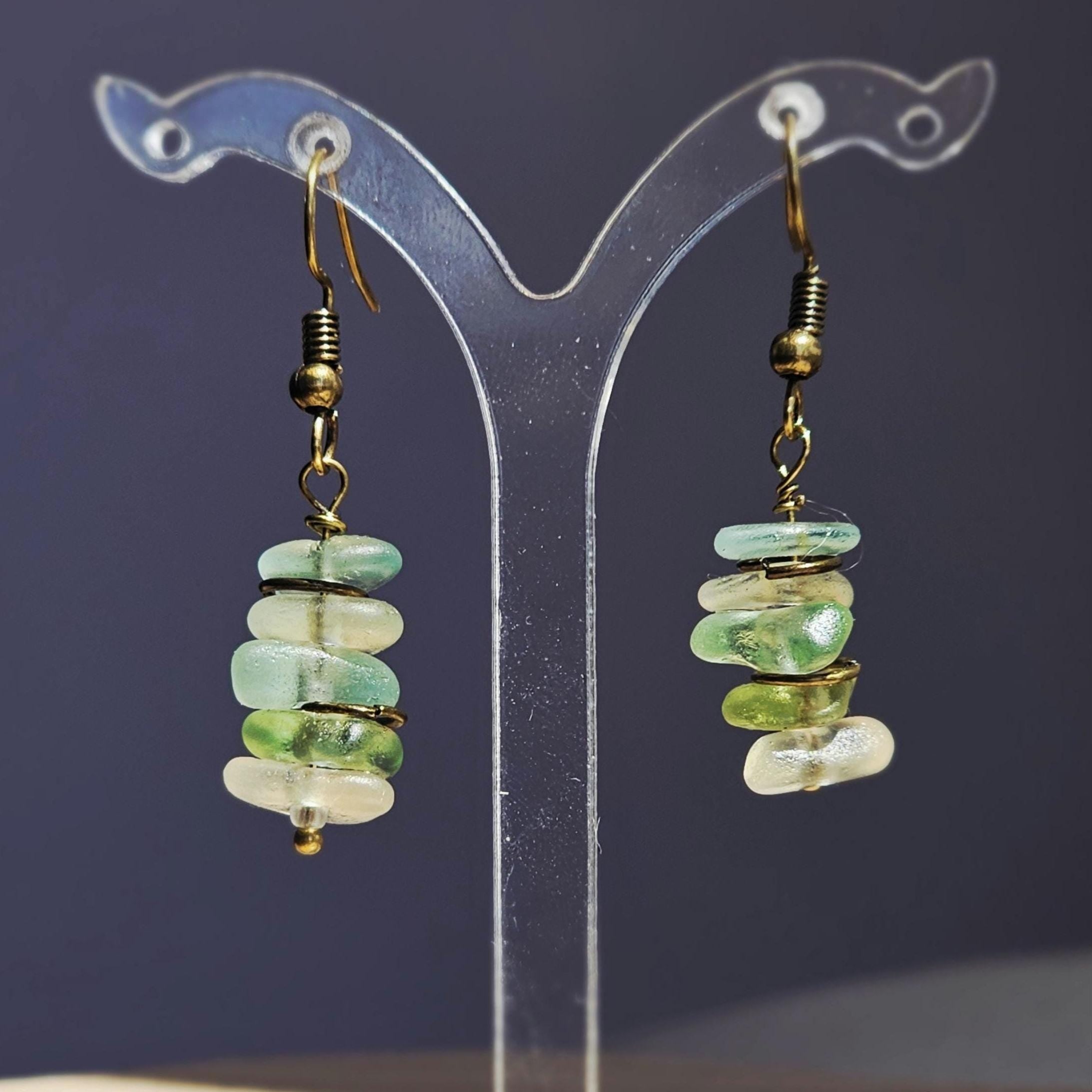 Pair of earrings with green, aqua and clear sea glass on a dark backgroud