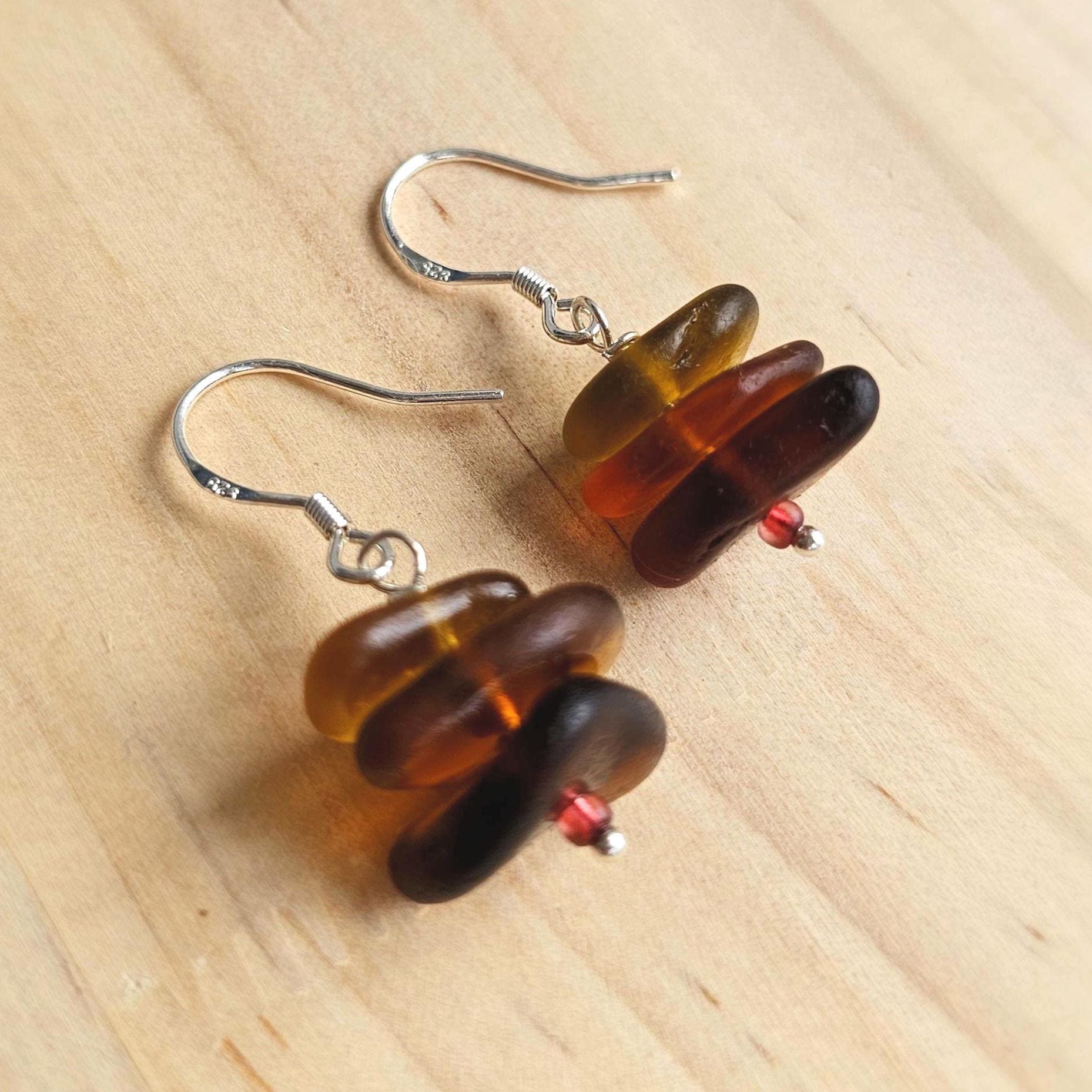 Pair of brown sea glass earrings on a wooden surface