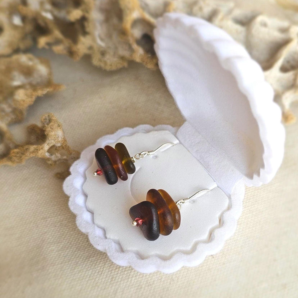 Jewelry with amber sea glass on a white shell against a beige background